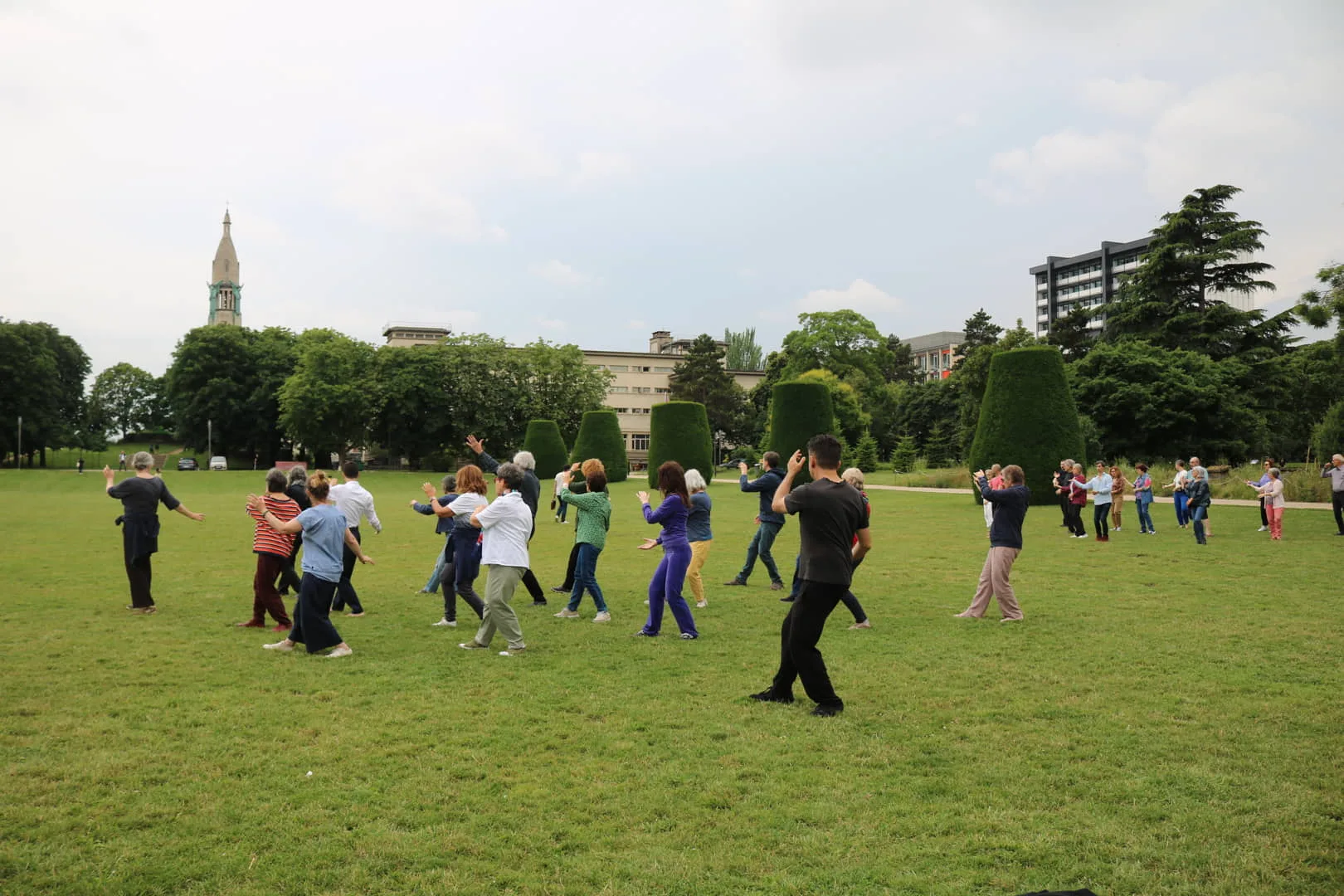 deux groupes d'hommes et de femmes pratiquants du Tai Chi à la cité universitaires. un groupe de pratiquants avancés au premier plan, un groupe de débutant au fond
